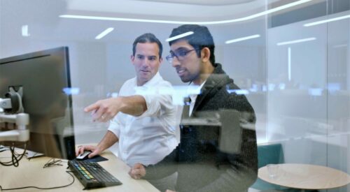 Man pointing at screen to show coworker something