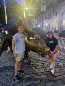 Two people posing next to a bull statue