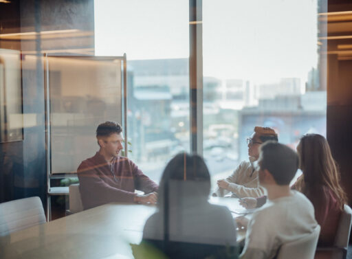 Photo of five people sitting around a table in a conference room