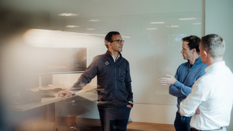 Photo of three people standing by a desk